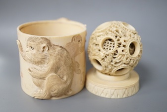 A late 19th century Chinese carved ivory concentric ball comprising seven reticulated spheres, with a small stand, and a Japanese carved ivory box (base missing), Meiji period, of cylindrical form, decorated with a black